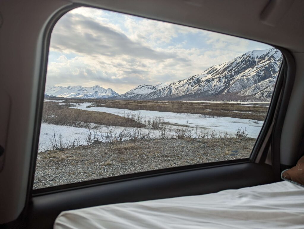 Bivouac avec vue sur les montagnes enneigées d'Alaska depuis l'intérieur d'un van