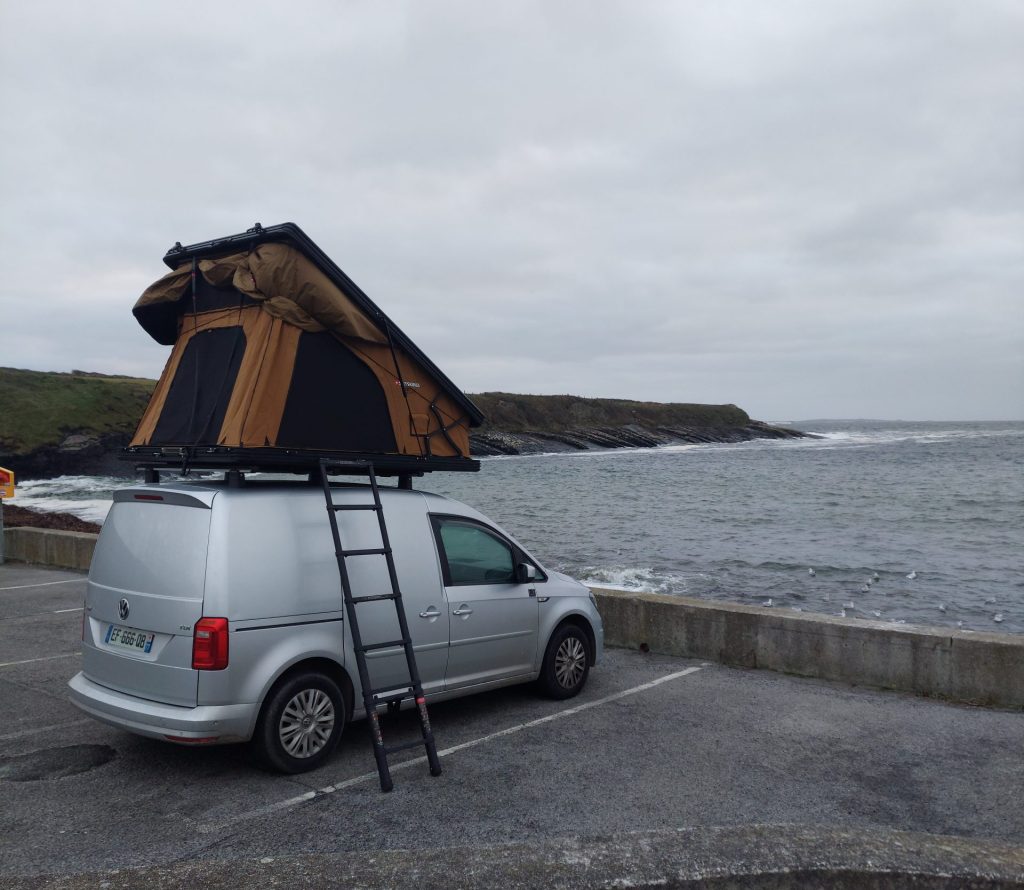 utilitaire avec tente de toit garé face à la mer